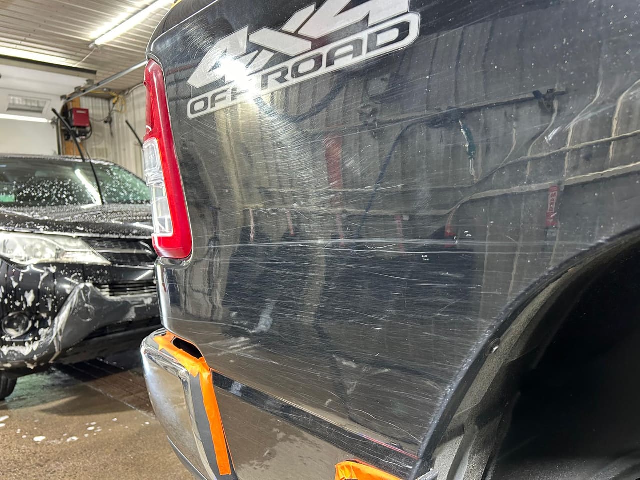 Côté de la caisse d’un RAM 1500 noir, sous l’autocollant « 4x4 Off Road », la peinture striée de rayures